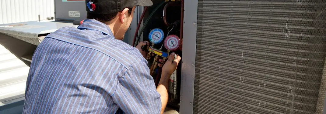 HVAC technician servicing a condenser unit in Rosedale