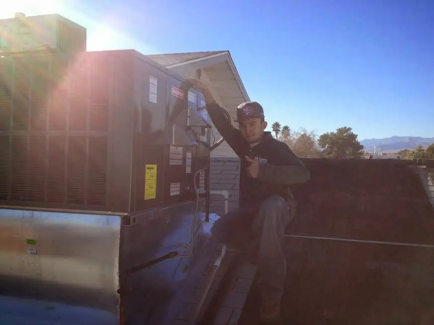 HVAC technician performing Heat Pump Repair on a rooftop unit in Rosedale